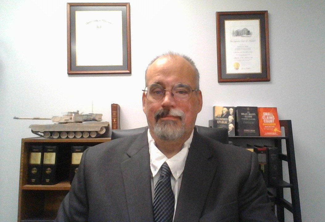 Patrick Nolan at his desk, Missouri statutes and an Abrams model on the shelf behind him