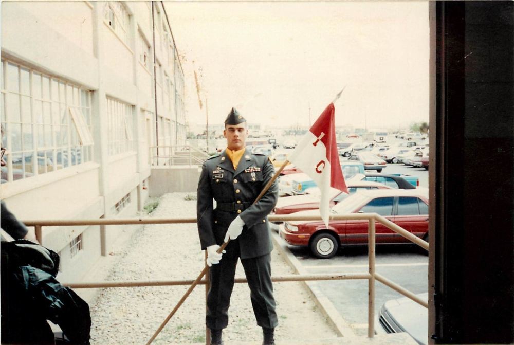 In dress greens carrying the company guidon